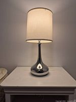 Full view of lamp lit on table showing shade and base