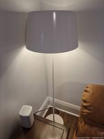 Full view of white metal floor lamp beside chair and table