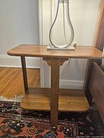 Front view of vintage walnut side table with lamp on top