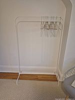 Front view of white metal garment rack with hangers