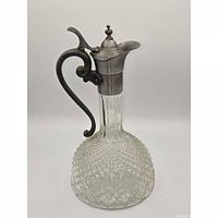 front view of diamond-cut glass claret jug with pewter lid and handle