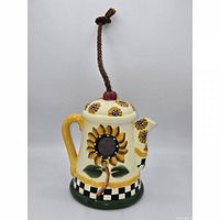 Front view showing sunflower entrance, spout, handle, rope hanger