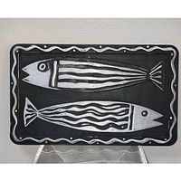 front view showing black rectangular trivet with silver fish design and wavy border