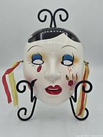 Front view of painted ceramic mask on stand
