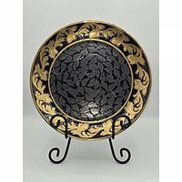 front view of black and gold baroque plate on stand