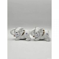 Two white ceramic elephant figurines side by side, front angle