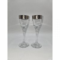 Front view of two clear cordial glasses with platinum etched rims and twisted stems
