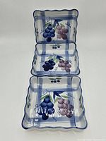 Three square ceramic grape-design dishes stacked vertically