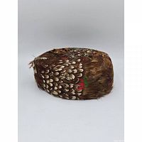 Side view of feather-covered pillbox hat showing color pattern and profile