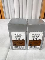 Front view of two grey Oticon battery cartons