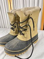 Three-quarter view of both boots showing leather uppers, rubber lowers, laces, and shearling lining