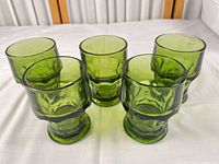 Five green pressed glass tumblers grouped together