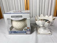 Boxed Yankee Candle Scenterpiece MeltCup warmer beside ceramic lotus warmer