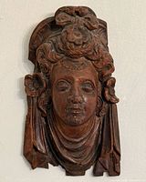 Front view of carved wood woman face plaque