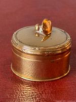 Side view of gold-filled box showing cylindrical form and finial knob