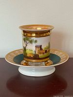 Cup on saucer, frontal hand-painted scene visible