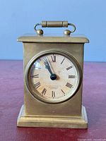 Front view of brass carriage clock showing dial and handle