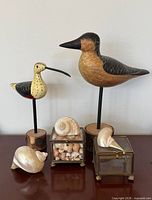 Group shot of both wood birds, glass boxes, large shells and assorted shells