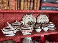 Full tea set on shelf: teapot, sugar jars, cups, saucers, plates