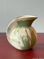 Front view of marbled green and cream pottery vase with curling spout
