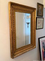 Full view of rectangular gilt mirror on wall