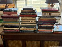 Three tall stacks of hardcover and coffee-table books on cabinet