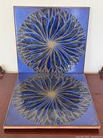 Two blue glazed tiles displayed upright and flat to show pattern