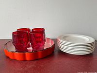Group view showing red tumblers, orange pie dish, stack of white plates