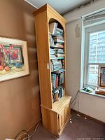 Full view of tall pine bookcase beside window