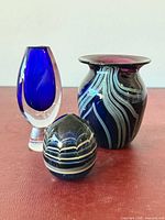 Group view of Kosta Boda vase, swirl art glass vase and striped paperweight