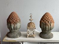 Pair of terracotta finials and metal lantern on surface