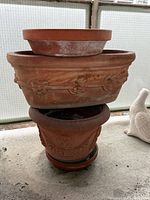 Stacked view of three planters and one saucer showing designs and weathering