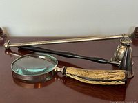 Magnifying glass and two candle snuffers grouped on surface