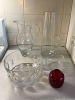 Group shot of two pitchers, fruit bowl, finger bowl, red vase