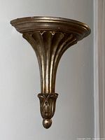 Front angled view of gilt carved wood wall shelf mounted on wall