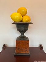 Front view of urn on pedestal with artificial lemons