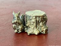 Front view of silver-plated squirrel inkwell beside tree stump