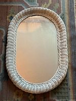 Front view of oval mirror showing full wicker frame and glass