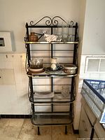Full view of 4-tier wrought iron baker’s rack with glass shelves