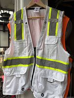 Front view white mesh reflective vest with neon yellow-grey stripes hanging on hanger