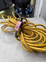 Coiled yellow extension cord showing connector end and overall wear
