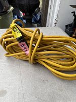Coiled yellow 50-ft extension cord with three-prong plug visible