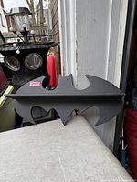 Front view of black Batman-shaped shelf on table