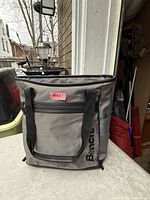 Front view of grey Bench cooler backpack with front zip pocket and handles