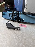 Front view of mirror dash cam with coiled power cord and plug visible