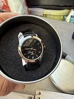 Watch inside tin showing dial, strap and foam insert