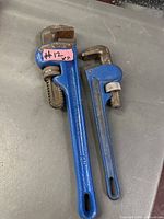 Two blue pipe wrenches laid side by side showing overall size and condition