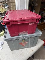 Stacked red and grey plastic totes with folding lids