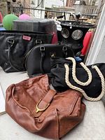 All four handbags grouped: black tote, black dome satchel, black canvas rope-handle bag, brown leather bag