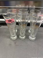 six tall gold-rimmed Olympic glasses grouped on table